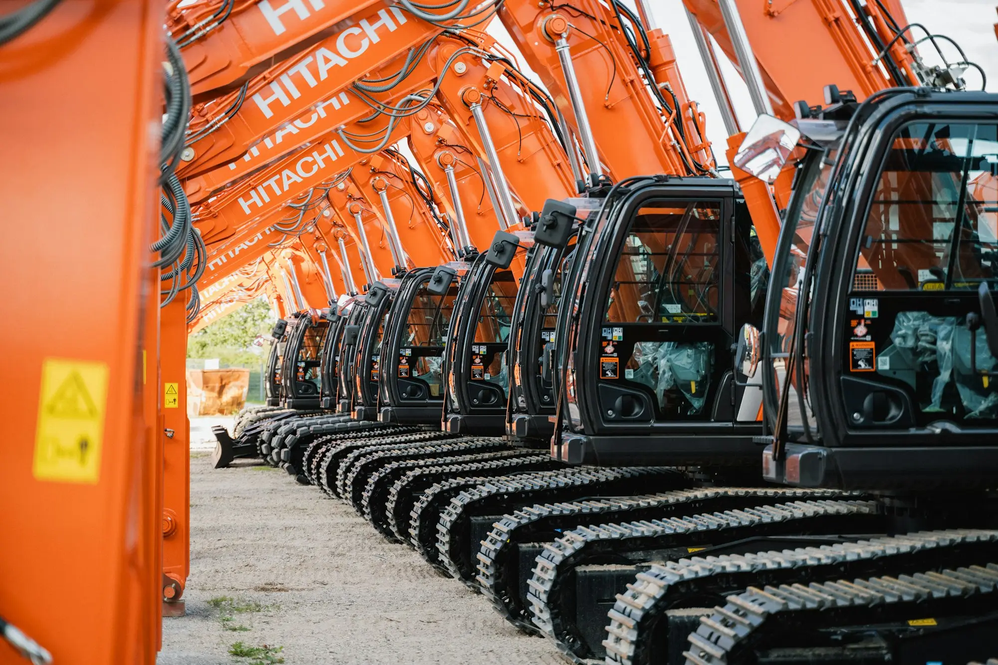 Row of orange excavators parked in an equipment yard, the kind of owned plant a business can borrow against