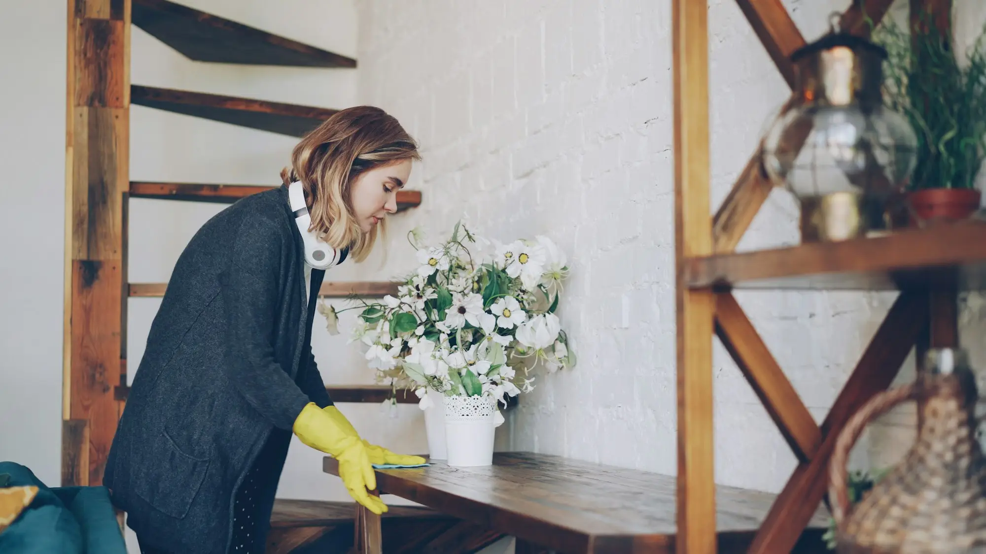 Shop owner in yellow gloves tidying a timber shelf display of stock before a stocktake
